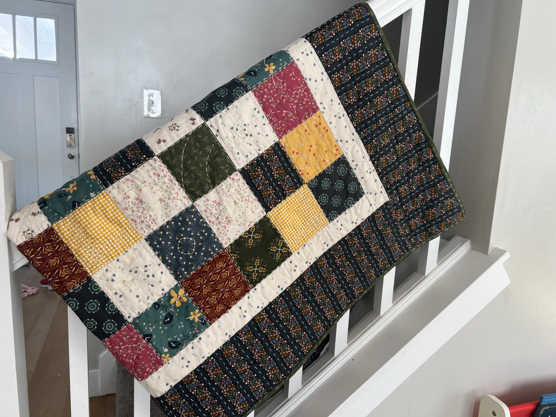 Colorful patchwork quilt draped over a white stair railing